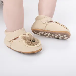 Detalle de cerca de zapatos de bebé beige para primeros pasos con un lindo parche de conejito