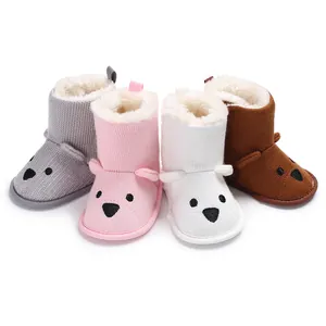 Detailansicht von gestrickten Bären-Babystiefeln in Grau, Rosa, Weiß und Braun mit Fellfutter.
