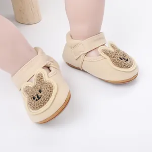Primer plano de zapatos beige para bebés con un lindo diseño de conejo de peluche.