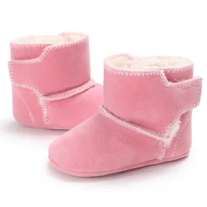 Detail van roze suède babylaarsjes met zachte voering van imitatiebont en wit stiksel