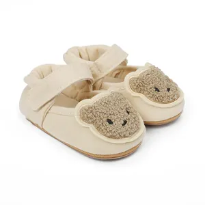Detailansicht beige Baby Lauflernschuhe mit süßem Teddybär Plüsch-Gesicht Design.