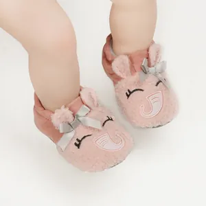 Detailed view of pink plush baby slippers with cute cartoon embroidery and ribbon bow