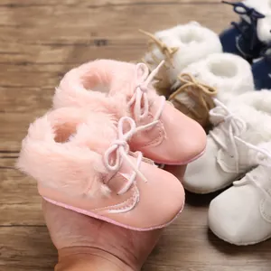 Close-up of pink faux fur-lined baby boots with soft soles and delicate lace-up design