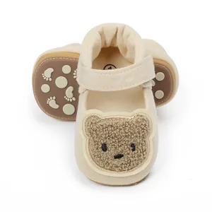 Detailaufnahme cremefarbener Lauflernschuhe mit süßem Bären-Stick und rutschfester Sohle