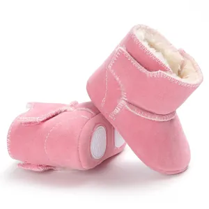 Close-up van roze suède babyschoentjes met zachte fleecevoering en antislipzolen.