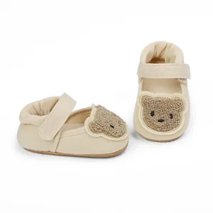 Close-up detail of infant walking shoes with cute cartoon bear patch decoration