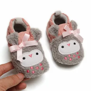 Detail of warm winter baby plush shoes with cute owl design and soft pink bow detail