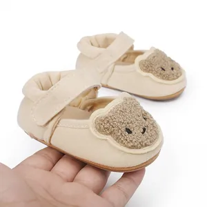 Hochwertige Nahaufnahme cremefarbener Baby-Lauflernschuhe mit Plüschbären-Motiv.