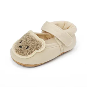 Detaillierte Nahaufnahme von cremefarbenen Baby-Lauflernschuhen mit süßem Bären-Patch