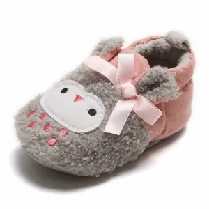 Detailed close-up of pink and gray plush baby shoes featuring a cute cartoon face and satin bow