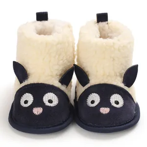 Gros plan de bottes de neige bébé en peluche avec un motif de mouton et semelles souples.