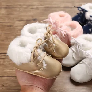 Close-up shot of golden baby faux fur boots with soft soles for infant pre-walkers