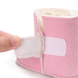 Primer plano de botas de invierno rosas para bebé con forro de piel blanca y velcro