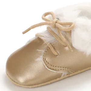 Macro detail of baby boot with golden metallic finish and white faux fur trim