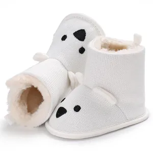 Nahaufnahme der weißen gestrickten Babystiefel mit weichem Fleecefutter und Bärendesign