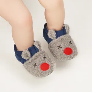 Detailed view of cartoon reindeer baby booties with soft fleece texture and blue trim.