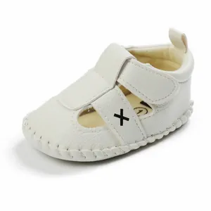 Detailed view of white infant walking shoe with soft leather texture and X stitch
