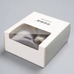 Nahaufnahme grauer gestrickter Babystiefel in einer weißen Premium-Geschenkbox