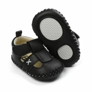 Detailed close-up of black synthetic leather baby walker shoes with cross-stitch.