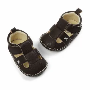 High-quality detail of dark brown baby walker sandals with white cross-stitch design