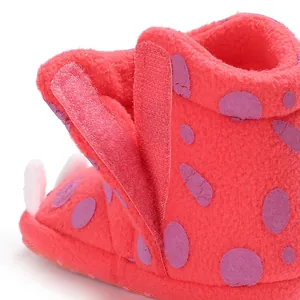 Close-up detail of fuzzy baby winter boots featuring pink fleece and purple dot patterns