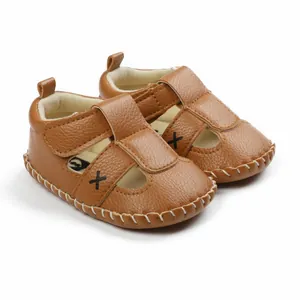 Macro detail of brown faux leather baby sandals featuring a T-strap and velcro closure.
