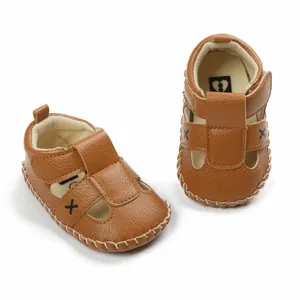 Close-up view of brown leather baby sandals with velcro straps and white stitching