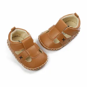 Detailed view of brown faux leather baby pre-walker sandals with X pattern