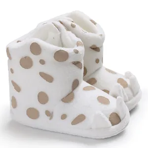 Close-up of white plush baby snow boots with cute claw design and polka dots