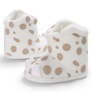 Close-up of plush white baby boots with brown polka dots and cute claw-shaped details.