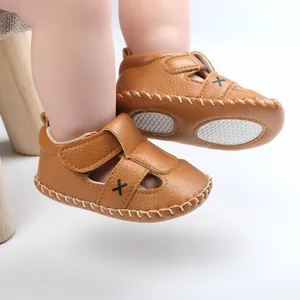 Close-up of brown faux leather baby sandals with velcro straps and non-slip soles.