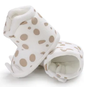 Close-up of warm white polka dot baby winter boots with soft plush interior and claws