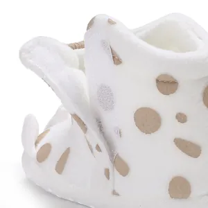 Detail view of soft velcro fastener on white plush baby boots with brown polka dots.