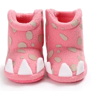 Close-up detail of pink baby snow boots featuring white dinosaur claws and soft fleece.