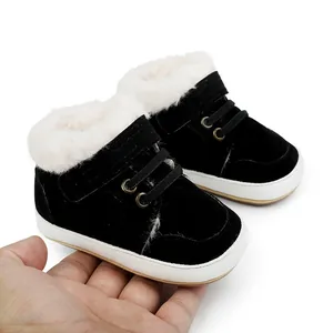 Schwarze Baby-Winterschuhe mit warmem weißem Plüschfutter in der Hand gehalten