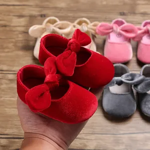 Detail view of soft red velvet baby shoes with decorative bow knots