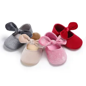 Detailed close-up of multi-color velvet baby shoes with large bows and soft soles.