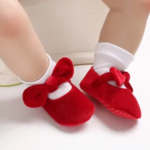 Macro view of red velvet baby princess shoes with decorative bows and soft soles