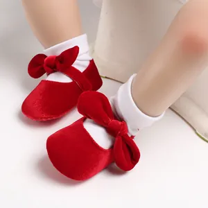 Close-up of red velvet baby princess shoes with large bow and soft sole detail