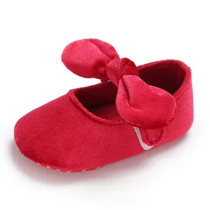 Detailed close-up showing the soft velvet texture and large bow on red baby girl shoes