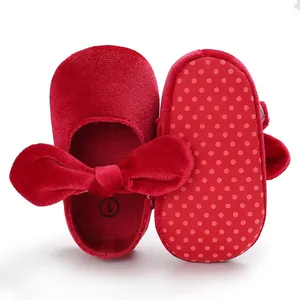 Macro view showing the red velvet texture and anti-slip dotted sole of baby walking shoes