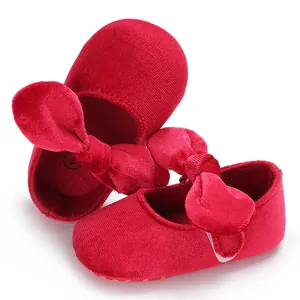 Close-up of red velvet baby princess shoes with large bow detail and soft soles