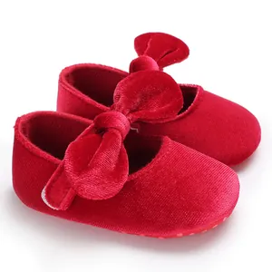 Close-up of elegant red velvet baby princess walker shoes with large bow detailing