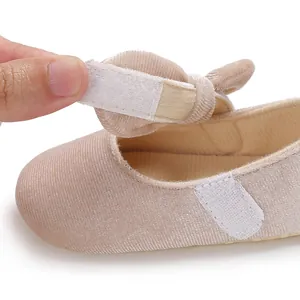 Close-up detail of the adjustable hook-and-loop strap on beige soft-sole baby shoes.