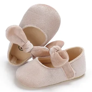 Macro view of pink velvet baby princess shoes with bow detail and soft soles.