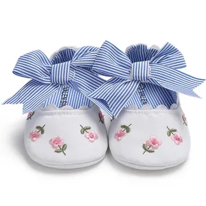 Vue détaillée de chaussures princesse bébé blanches avec broderie florale et nœud rayé bleu