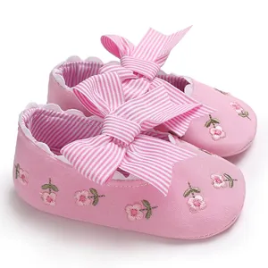 Gros plan de chaussures de princesse roses pour bébé avec broderie florale et nœuds