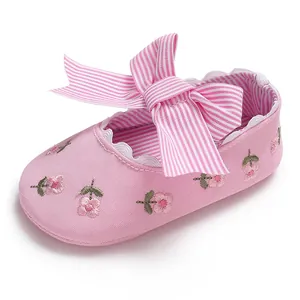Détail d'une chaussure de princesse rose pour bébé avec broderie florale et nœud rayé