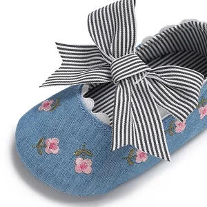 Détail de chaussure de bébé fille en jean avec broderie florale et grand nœud rayé