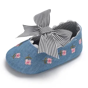 Gros plan de chaussure bébé fille en denim bleu avec broderie et nœud rayé